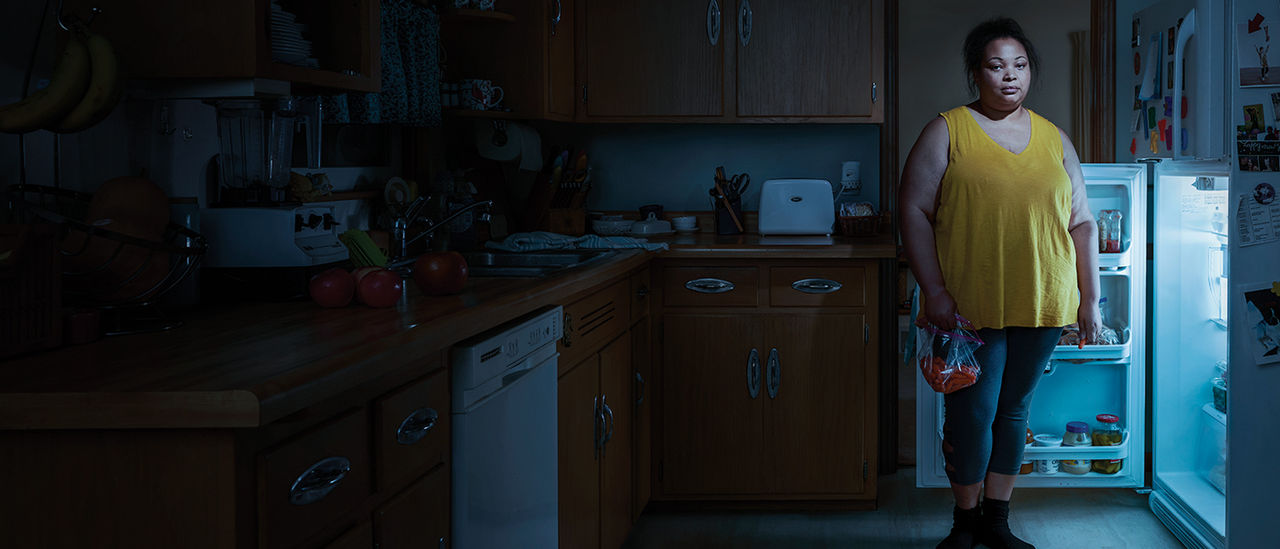 Woman standing in front of open refrigerator. 